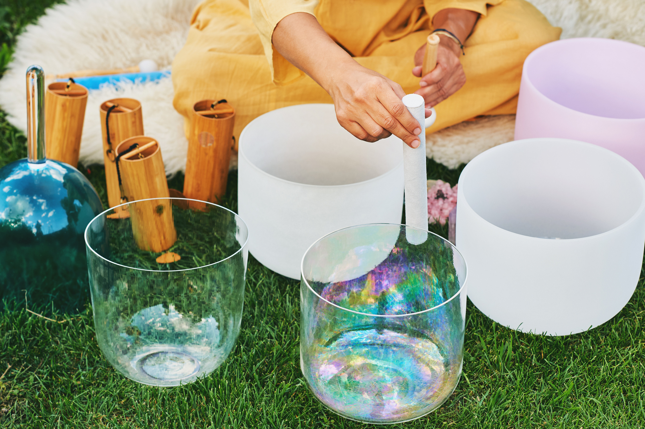 Woman playing music on crystal singing bowls, relaxing in beautiful green garden